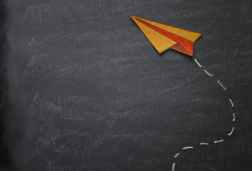 Top view image of paper plane over classroom blackboard background.