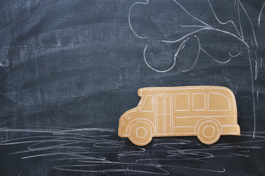 Back to school concept. Top view image cardboard school bus over classroom blackboard background.