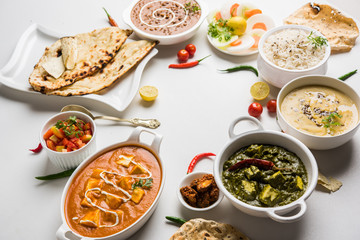 Assorted indian food for lunch or dinner, rice, lentils, paneer, dal makhani, naan, chutney, spices over moody background. selective focus   © StockImageFactory