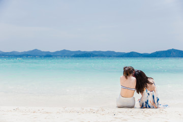 Fototapeta na wymiar Two young women lying on a tropical beach. Blue sea in the background. Summer vacation concept.