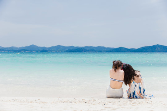  Two young women  lying on a tropical beach. Blue sea in the background. Summer vacation concept.