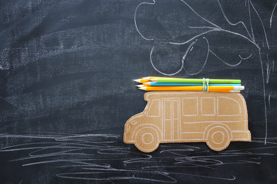 Back to school concept. Top view image school bus and pencils over classroom blackboard background.