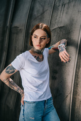 attractive stylish woman with tattoos posing and looking away