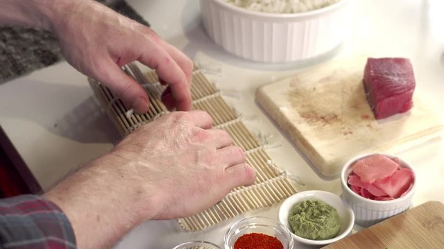 Sushi chef using bamboo mat to make fresh sushi roll