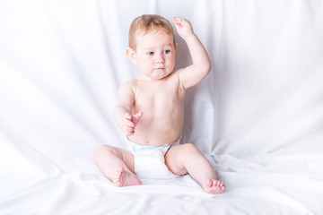 Cute blue-eyed baby 6-9 months smiling and playing on white background. Children's emotions and gestures