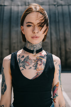 Portrait of young woman with tattoos looking at camera