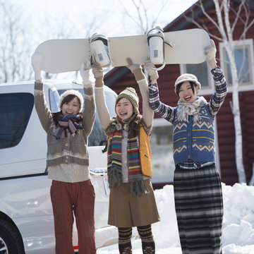 スノーボードを持ち微笑む3人の女性