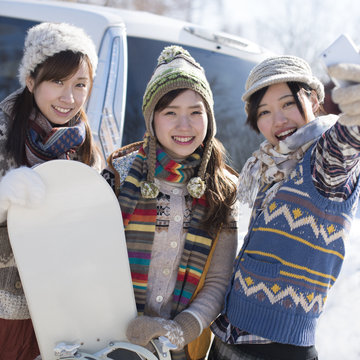 スノーボードを持ち自分撮りをする3人の女性