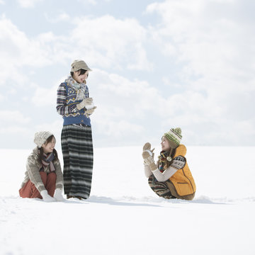 雪原で雪玉を作る3人の女性
