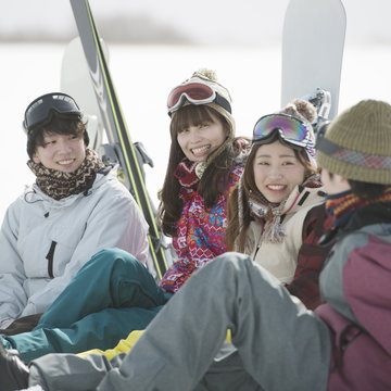 雪原に座り談笑をする若者たち