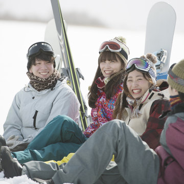 雪原に座り談笑をする若者たち