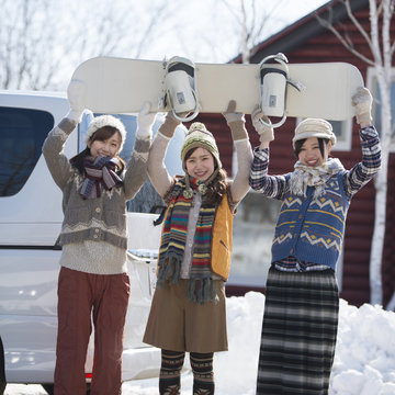 スノーボードを持ち微笑む3人の女性