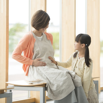 母親のお腹に手をあてる女の子