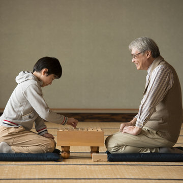 和室で将棋をする祖父と孫
