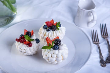 Delicate white meringues with fresh berries on the plate. Dessert Pavlova. White background. Wedding cake.