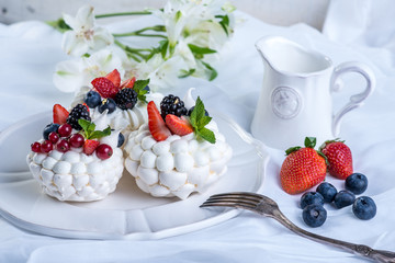 Delicate white meringues with fresh berries on the plate on white background. Dessert Pavlova. Wedding cake.