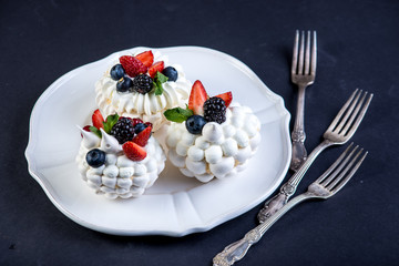 Delicate white meringues with fresh berries on the plate. Dessert Pavlova close-up. Wedding cake.