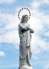 Statue of Virgin Mary as a symbol of love and kindness near catholic church. - obrazy, fototapety, plakaty