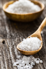Sea salt  in a spoon on wooden table