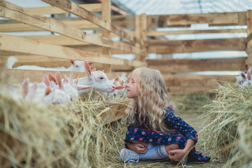 side view of child going to kiss goat at farm - Powered by Adobe