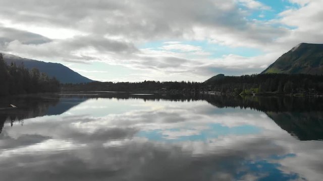 Slow Motion Rising into Cloudy Blue Sky from Beautiful Calm Blue Water Lake