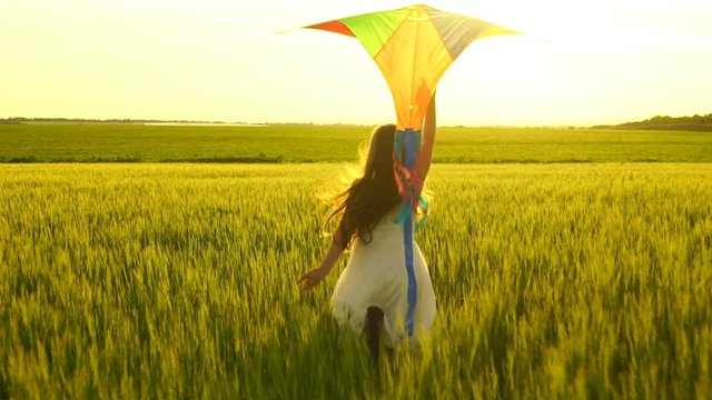girl running around with a kite on the field.