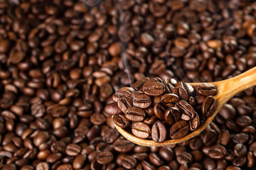 Roasted coffee beans in a wooden spoon, closeup.