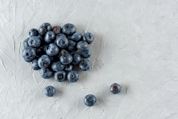 Blueberry on a gray cement background. Ripe and juicy fresh blueberry close-up. A bunch of berries close-up.