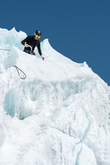 A professional mountaineer in a helmet and ski mask on the insurance does notch the ice ax in the...