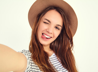 pretty girl in summer hipster clothes take selfie from hands with phone, showing her tongue