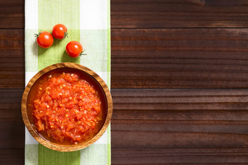 Homemade traditional Italian marinara or pomodoro tomato sauce made of fresh tomato, garlic, dried oregano and salt, photographed overhead on dark wood with natural light