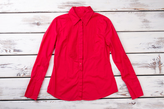 Red casual women shirt. Bright wooden desks surface background.