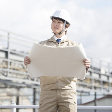工事現場で図面を持つ作業員