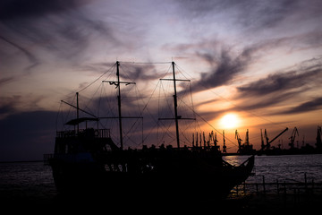 Silhouette of a large, old ship at the dock at sunset. bright beautiful sky