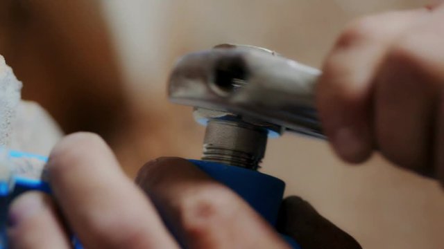 Worker's hands screwing the nut with a large wrench close-up