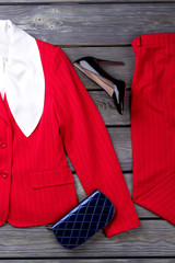 Top view red women's business outfit. Flat lay, grey wooden surface background.