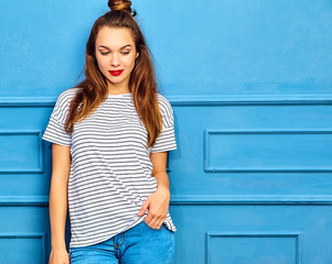 Young stylish girl model in casual summer clothes with red lips, posing near blue wall