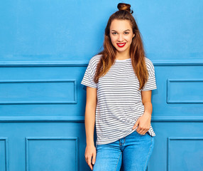 Young stylish girl model in casual summer clothes with red lips, posing near blue wall