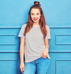 Young stylish girl model in casual summer clothes with red lips, posing near blue wall