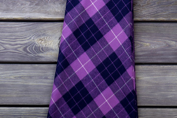 Close up checkered cloth material on wooden background. Purple cotton clothes on the table.