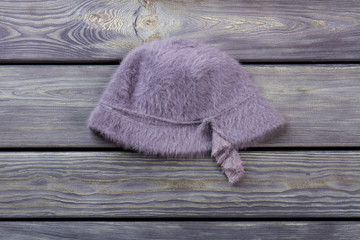 Woolen hairy purple hat. Flat lay, wooden desk surface background.