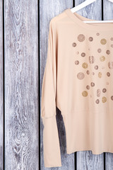 Beige women's blouse sleeve, top view. Wooden desk surface background.