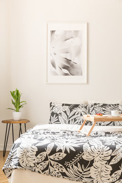 Floral sheets on the bed with a wooden tray in a bright bedroom interior