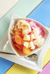 High angle view of a bowl of fruits dessert with ice on colorful wooden table