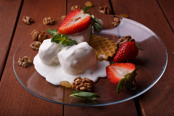 melted ice cream in transparent bowl, decorated with strawberries and biscuit