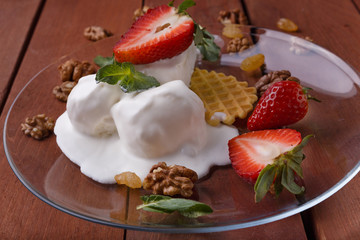 melted ice cream in transparent bowl, decorated with strawberries and biscuit