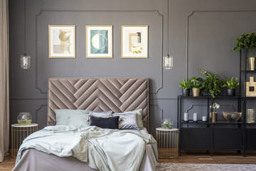 Dark grey bedroom interior with wainscoting on the wall, king-size bed with soft bedhead, three...