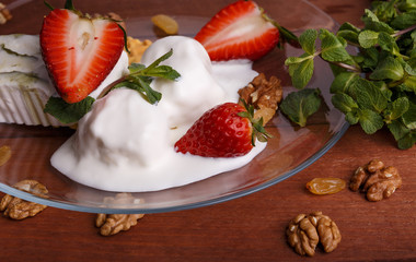 melted ice cream in transparent bowl, decorated with strawberries and biscuit