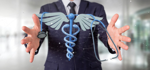 Businessman holding a 3d redering medical cadaceus and stethoscope
