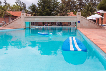 Blue surfboard floating on blue pool surface